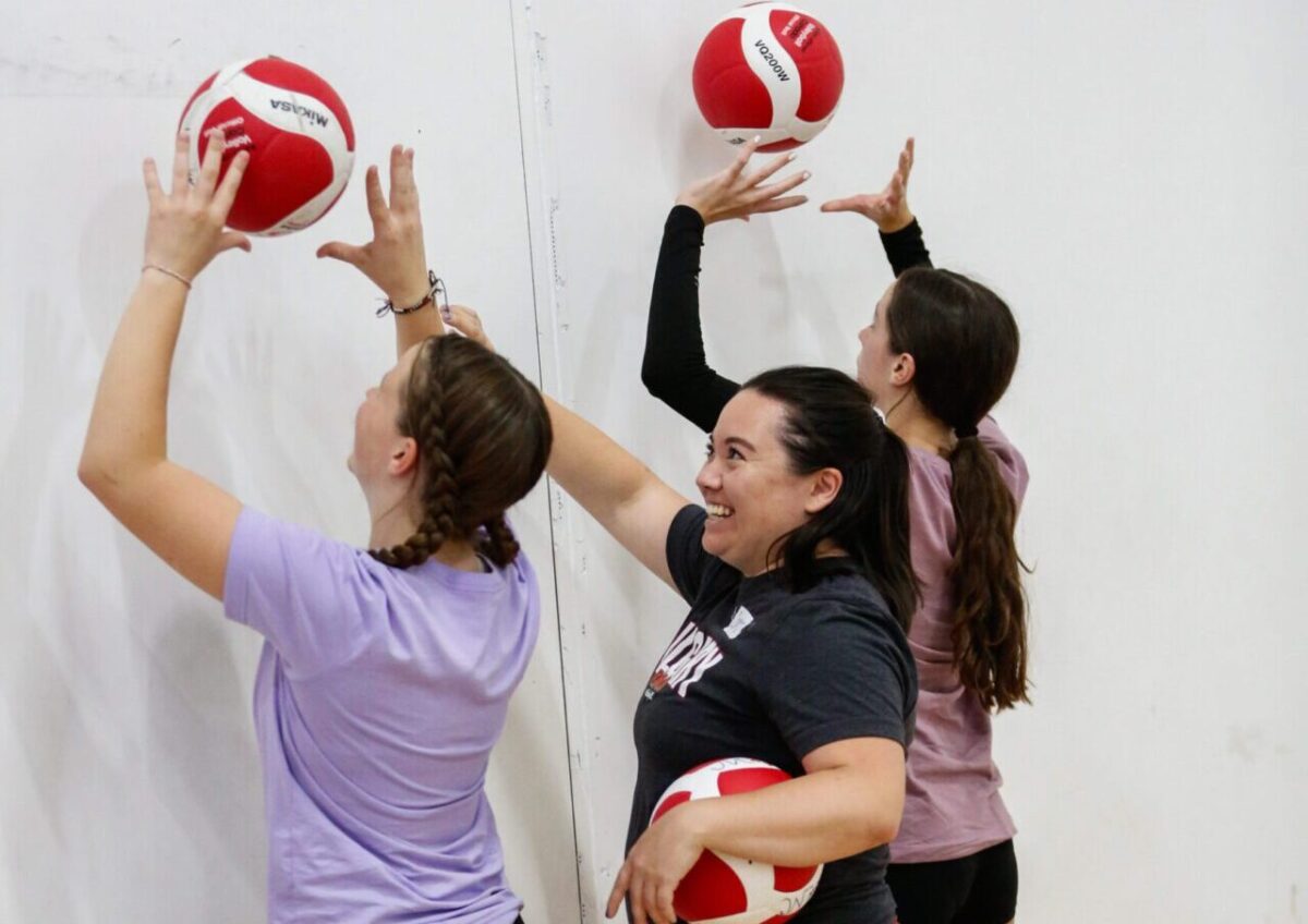 2 girls with their coach practicing volleyball wall drills