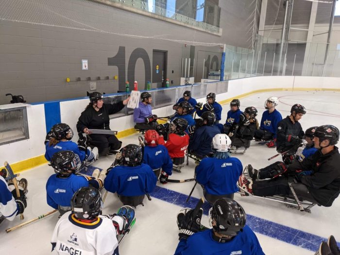 Coach on ice with para hockey athletes