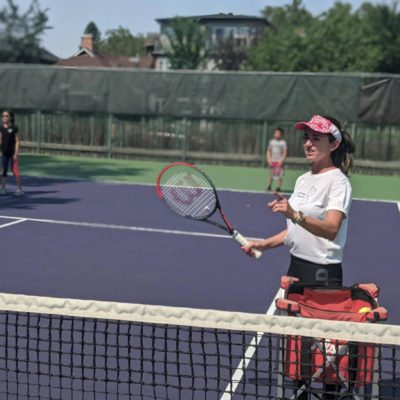 Tennis coach at the net serving tennis balls