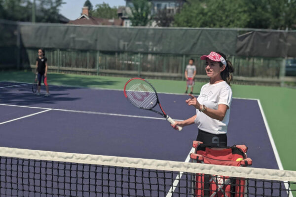 Tennis coach at the net serving tennis balls