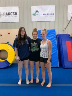 3 women gymnastic coaches in a gym