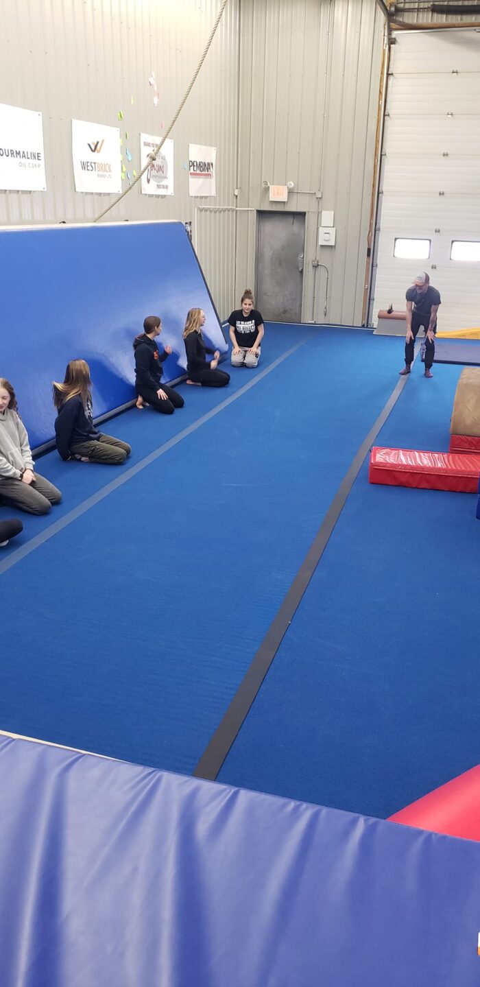 Group listening to an instructor on a gymnastics mat