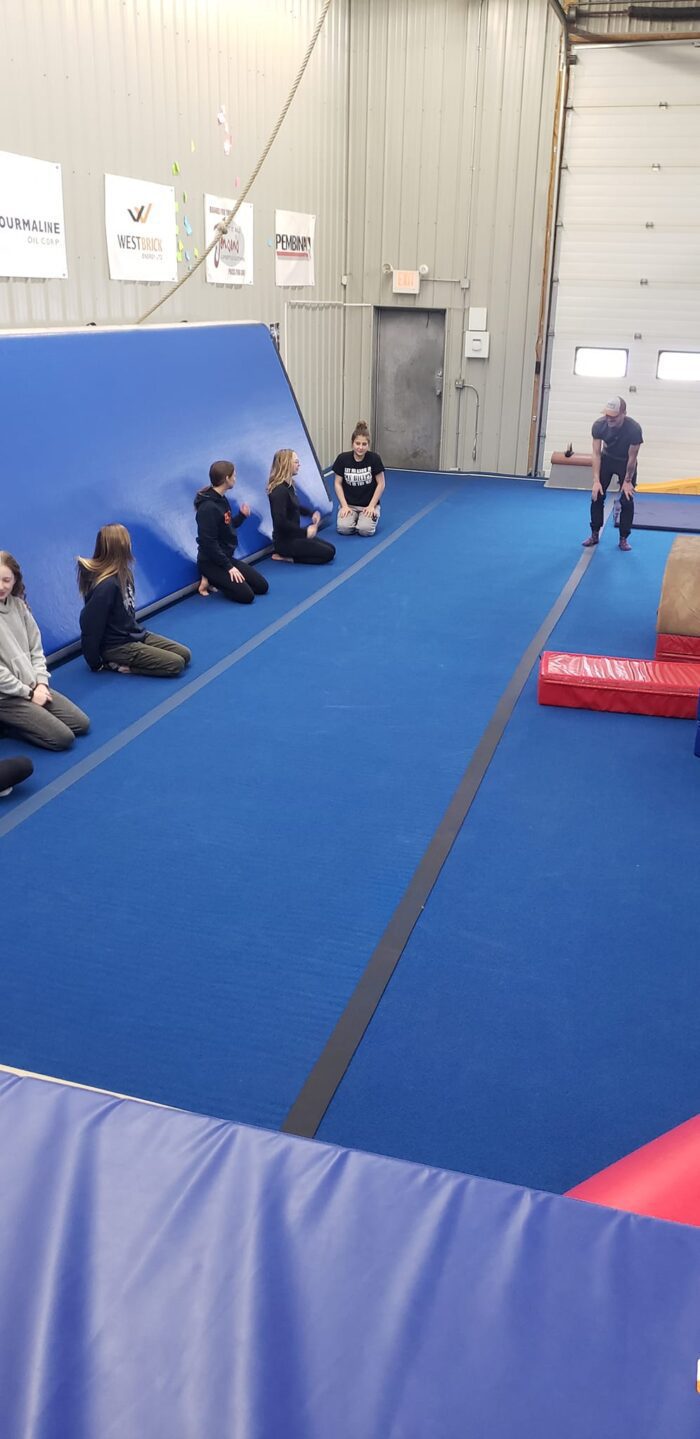 Group listening to an instructor on a gymnastics mat