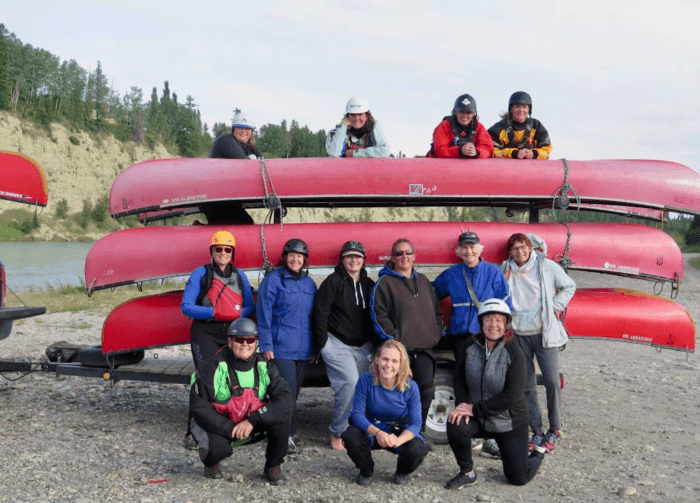 Group of women posed in front of canoes.