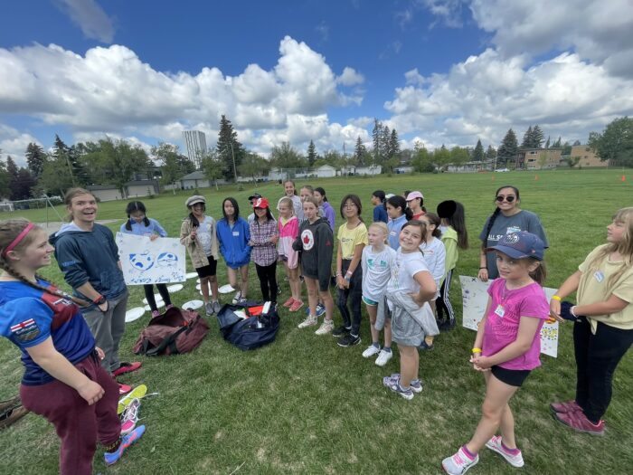 Girls on a field listening to a coach.