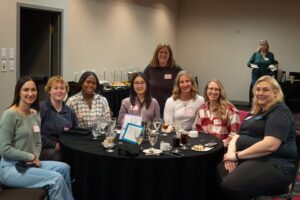 Group of women at a table taking a photo.