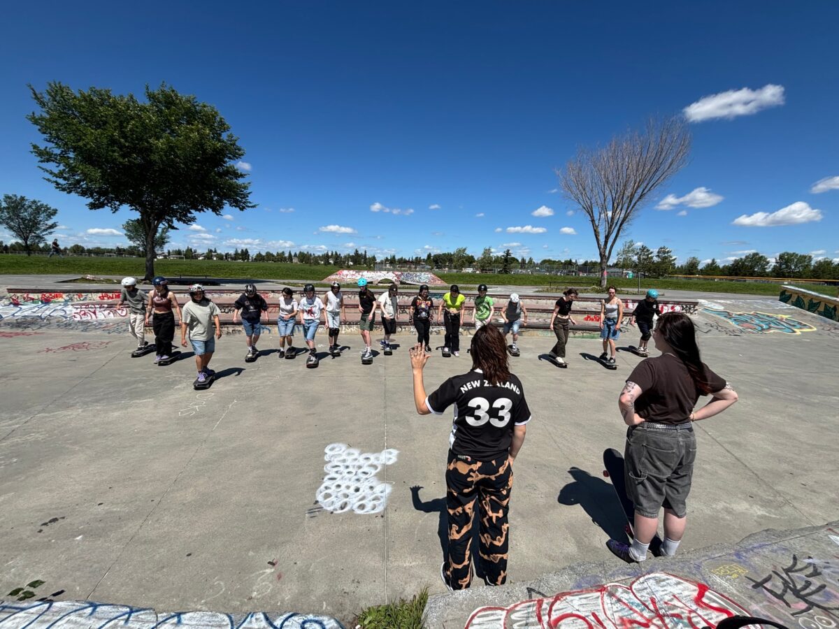 Group of women skateboarders in a circle in a cement skate park.