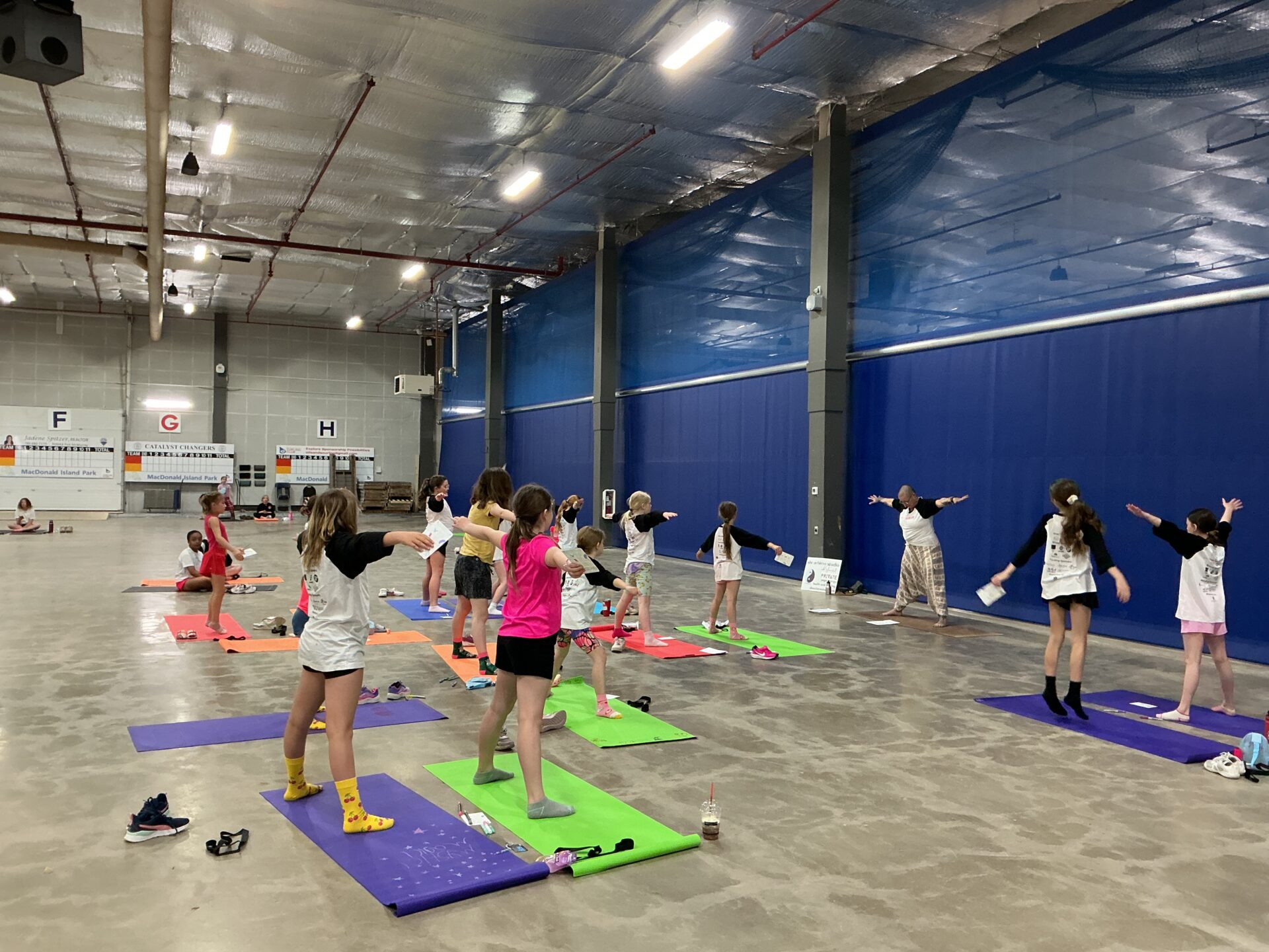 Group of girls in an indoor field house learning yoga.