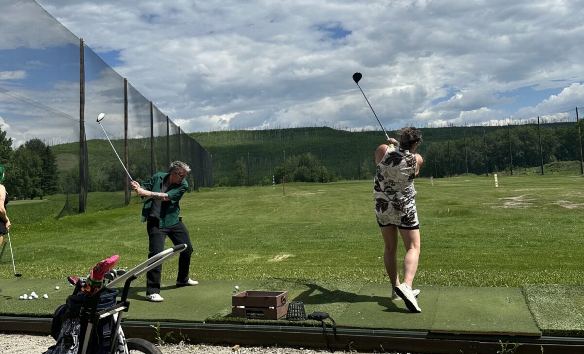 Two people at a outdoor driving range.