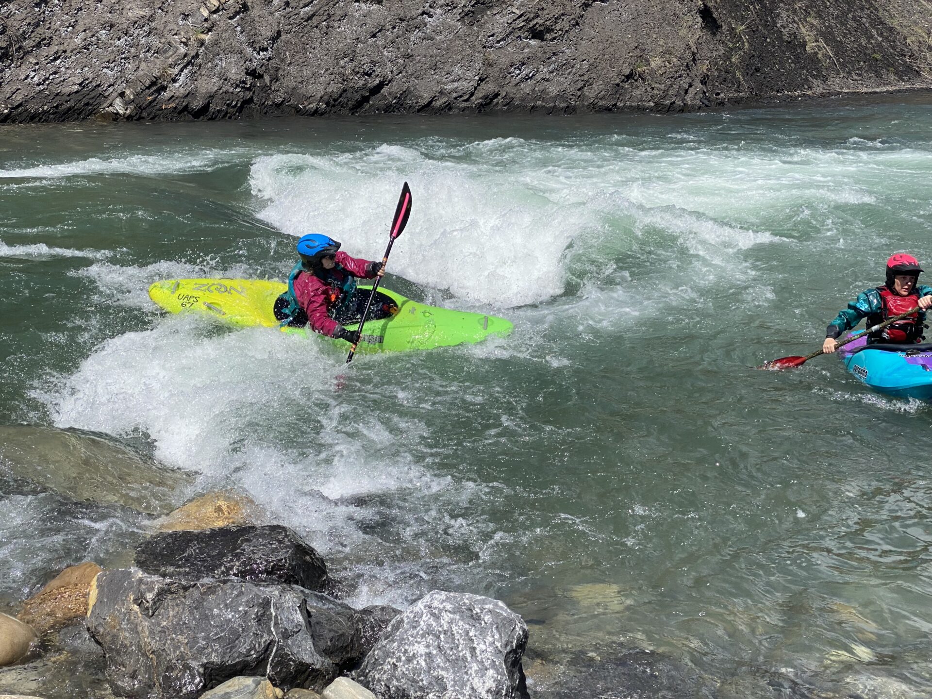 Two kayakers navigating river rapids.